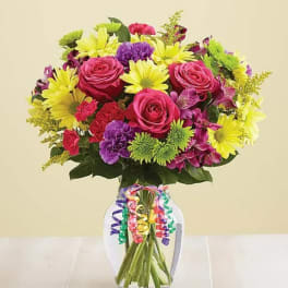 Bouquet of pink roses, yellow daisies, and purple flowers in a glass vase