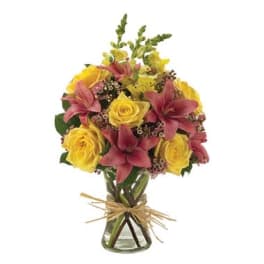 Bouquet of yellow roses and pink lilies in a glass vase
