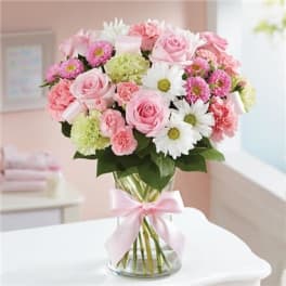 Pink and white bouquet in a clear glass vase with a pink ribbon