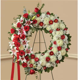 Large red and white floral wreath on a stand with a red ribbon