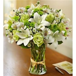 White lilies and green roses in a clear glass vase