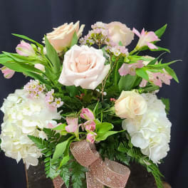 Pink and white roses arranged with hydrangeas in a glass vase