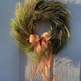 Pine wreath with a copper ribbon bow and pinecones