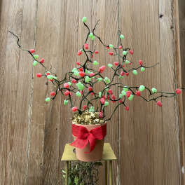Potted decorative branch arrangement with red bow and pink and green accents