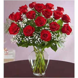 Red roses arranged in a clear glass vase with baby's breath