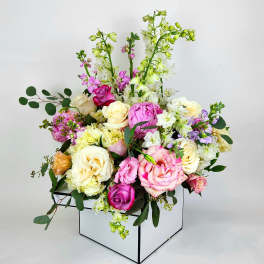 Mixed pink, cream, and white flowers arranged in a white box