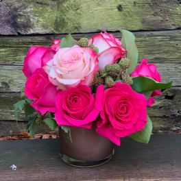 Pink and white roses arranged in a small glass vase
