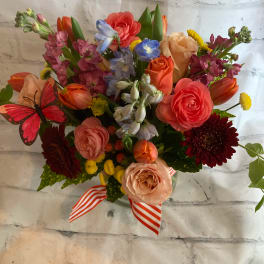 Mixed bouquet of colorful flowers with a striped ribbon and butterfly decoration