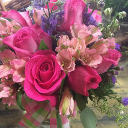 Pink roses and pale pink flowers with purple accents in a hand-tied bouquet