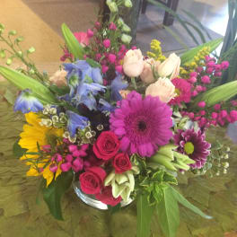 Mixed bouquet in a glass vase with pink, blue, yellow, and white flowers