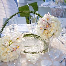 White rose and orchid table centerpiece with curved grass loops