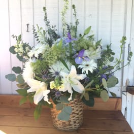 Tall white and purple mixed flower arrangement in a woven basket