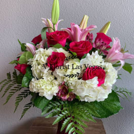 Pink roses and lilies with white hydrangeas in a red vase