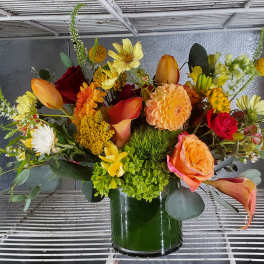 Mixed bouquet in a glass vase with orange, yellow, red, and white flowers