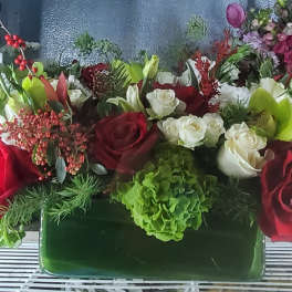 Mixed bouquet of red, white, and green flowers in a rectangular vase