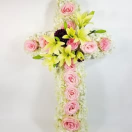 Floral cross with pink roses and pale lilies on a white background