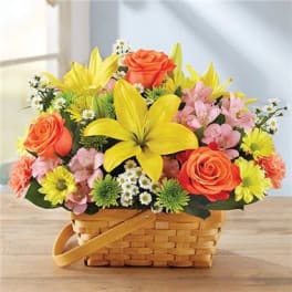 Basket of orange roses, yellow lilies, and pink flowers