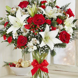 Bouquet of red roses and white lilies in a glass vase with a red ribbon