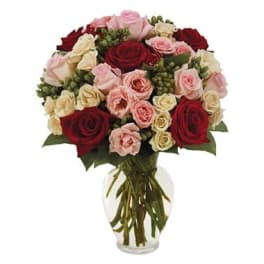 Bouquet of red, pink, and cream roses in a clear glass vase
