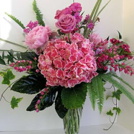 Pink floral arrangement in a clear glass vase with roses and hydrangea