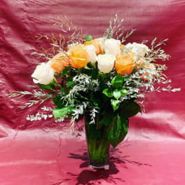 Custom Arrangement of white roses, peach roses & greens in clear glass vase with leaf wrap
