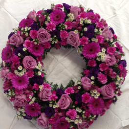 Circular wreath of pink and purple flowers on white fabric