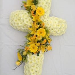 Cross-shaped floral arrangement with white chrysanthemums and yellow lilies and daisies