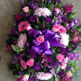 Purple and pink floral wreath with a large ribbon bow