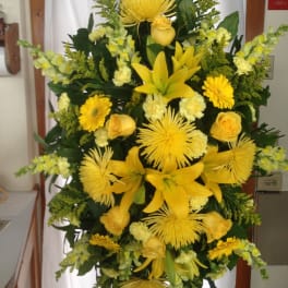 Tall yellow floral standing spray with lilies, roses, and daisies