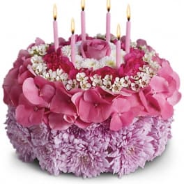 Pink floral cake with lit candles on top