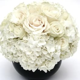 White roses and hydrangeas in a black vase