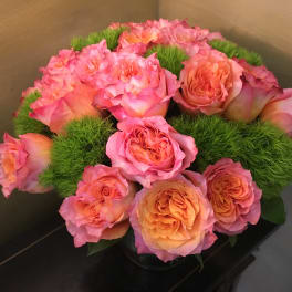 Pink and peach roses arranged with green moss in a low container