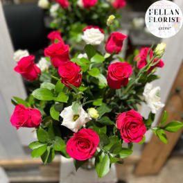 Arrangement of bright pink roses and white lisianthus in a clear glass vase