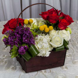 Basket arrangement of red and white roses with purple flowers
