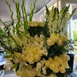 Large white floral arrangement with roses, lilies, and tall snapdragons