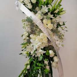 Tall white floral standing spray on an easel with a ribbon sash