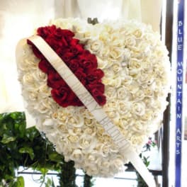 Heart-shaped rose wreath with red and white roses and a diagonal ribbon