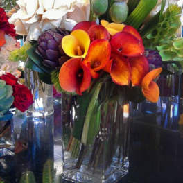 Bouquet of orange calla lilies and white blooms in a clear glass vase