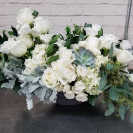 White rose arrangement with succulents and greenery in a low container