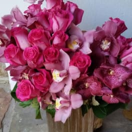 Pink roses and orchids arranged in a gold vase