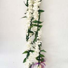 White flower garland with green leaves and a purple ribbon
