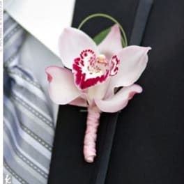Pink cymbidium orchid boutonniere on a black suit lapel with a striped gray tie.