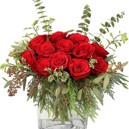 Low arrangement of red roses with assorted foliage in a square clear glass vase