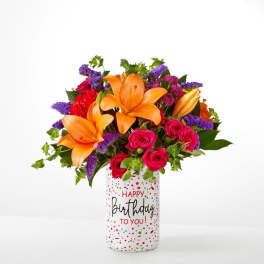 Bouquet of orange lilies and pink roses in a birthday vase