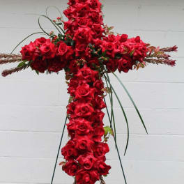 Red rose cross-shaped funeral spray on a stand with ribbon bows