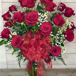 Bouquet of red roses with baby's breath and a red ribbon in a glass vase
