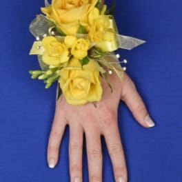 Yellow rose wrist corsage with ribbon on a person’s hand