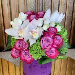 Pink and white roses with white orchids in a purple vase