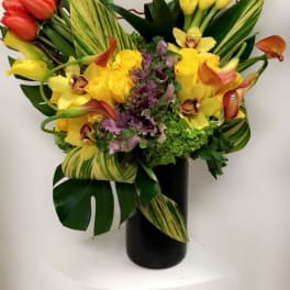 Colorful bouquet with tulips, calla lilies, orchids, and roses in a black vase
