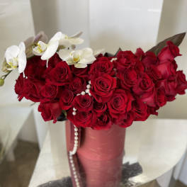 Red rose bouquet with white orchids in a pink vase